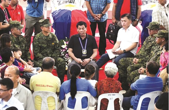 President Rodrigo Duterte talks with the families of three slain army soldiers, who according to authorities were killed by members of rebel group New Peopleu2019s Army (NPA) on Wednesday, the same day the group announced that it is terminating the unilateral ceasefire, during the soldiersu2019 wake at Camp Evangelista, Cagayan de Oro city, southern Philippines yesterday.