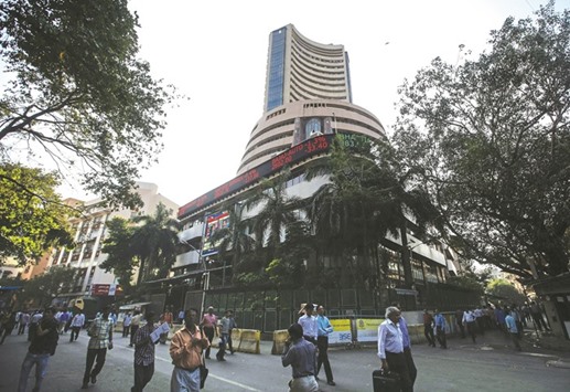 People walk by the Bombay Stock Exchange building in Mumbai. The BSE Sensex closed higher by 199 points to 28,439 yesterday.