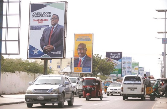 Motorists drive along a Mogadishu street sporting campaign billboards of presidential candidates.