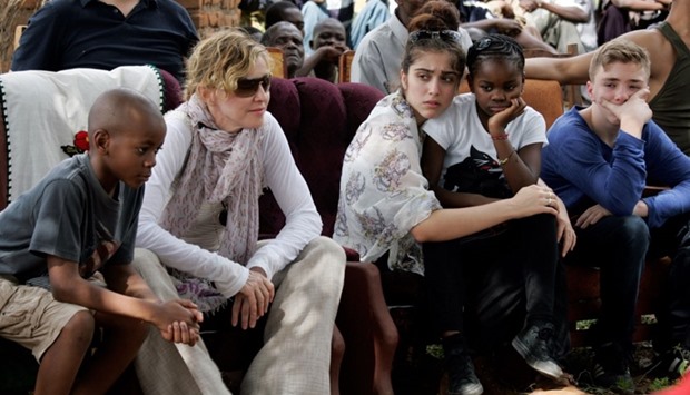 This file photo taken on April 2, 2013 shows US Pop Star Madonna (2nd L) sitting with her biological and adopted children (L to R) David Banda, Lourdes, Mercy James, and Rocco at Mkoko Primary School, one of the schools Madonna's Raising Malawi organization has built jointly with US organization BuildOn, during a visit in the region of Kasungu, central Malawi.