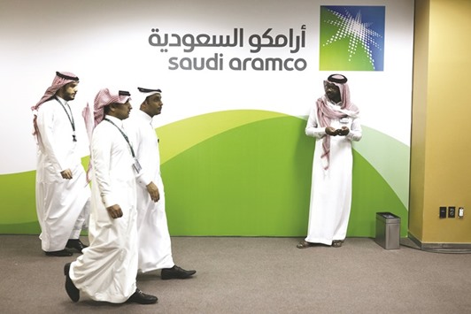 Attendees walk by a sign for the Saudi Arabian Oil Co (Aramco) on display inside the King Abdulaziz Center for World Culture during a tour of the project in Dhahran on November 25, 2016. Aramco is selling bonds as it prepares for a share sale in 2018 and follows the Saudi Arabian governmentu2019s debut offering in October which raised $17.5bn in the biggest-ever emerging-market sale.