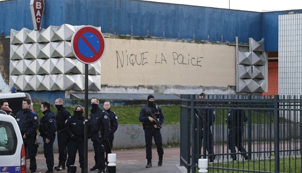 French policemen stand guard by a vandalised wall