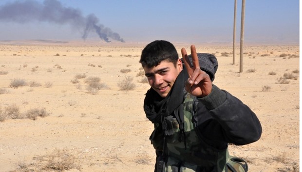 A member of the Syrian government forces flashes the sign for victory as they approach the strategic Jihar oil fields on the eastern outskirts of Homs.