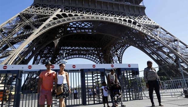 People walking past security gates at the Eiffel Tower.