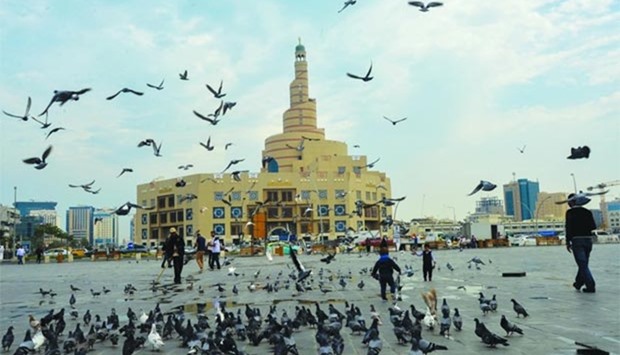 Pigeons gather near Souq Waqif while workers clear puddles caused by Thursday's drizzle in Doha. PICTURE: Noushad Thekkayil
