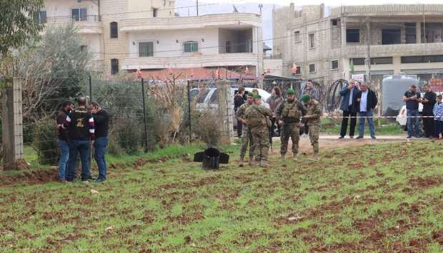 Lebanese security forces and Hezbollah agents stand next to a piece from a missile that landed on February 10, 2018 in the eastern Lebanese town of Rayak, near the border with Syria in the Bekaa Valley, after Israel's military attacked 12 Syrian and Iranian targets inside Syria. AFP