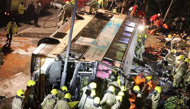 Firefighters and emergency personnel work at the site of an accident after a double-decker bus a toppled over along a road near the town of Tai Po in Hong Kong