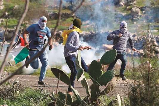 Palestinians run for cover from tear gas during clashes with Israeli soldiers in the village of Mugheer, about 25 kilometres northeast of the city of Ramallah, in the occupied West Bank, yesterday, following the funeral of a young boy reportedly killed by Israeli forces the previous night.