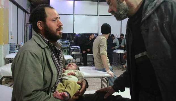 A Syrian man holds his infant who was rescued from under the rubble following air strikes on the rebel-held besieged town of Douma in the eastern Ghouta region, on the outskirts of the capital Damascus, as they await to receive treatment at a make-shift hospital late yesterday.