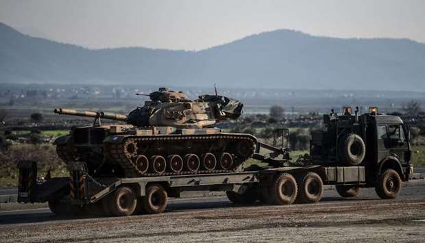 A Turkish military truck carries a tank as it is dispatched to the border in Hatay, near the Turkey-Syria border
