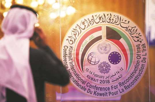 A Kuwaiti journalist speaks on his phone in front of the logo of the Iraq reconstruction conference at the media centre in Kuwait City  yesterday. The IFC has about $1.2bn in investments in different Iraqi ventures.