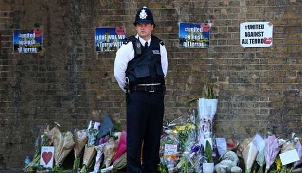 A police officer stands on duty near tributes and flowers at a police cordon in Finsbury Park area of north London on June 19, 2017, following a vehicle attack on pedestrians.