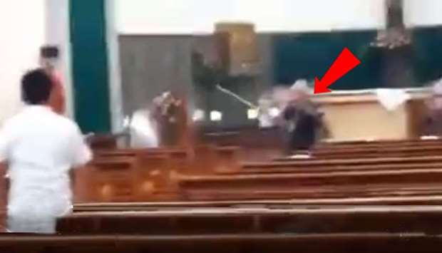 The attacker (pointed by the arrow mark) with a raised sword runs after a congregation member . Image grab from a video posted on Twitter.