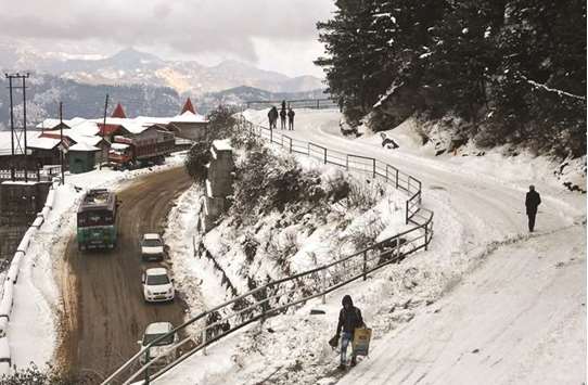 People walk on a snow-covered road after fresh snowfall on the outskirts of the hill town Shimla in Himachal Pradesh yesterday.