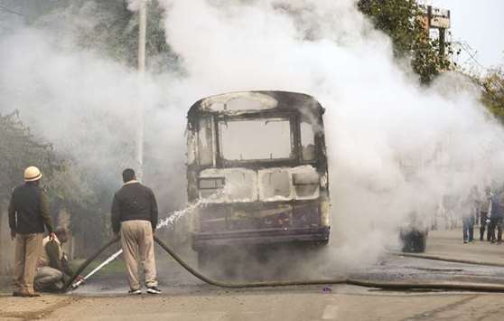 Firefighters extinguish a fire on a bus set by protesters near Allahabad University over the murder of a Dalit student.