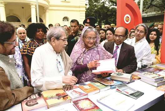 Prime Minister Sheikh Hasina looking at a book in a stall in a book fair she inaugurated yesterday as Cultural Affairs Minister Asaduzzaman Noor, Bangla Academy director general Shamsuzzaman and President Emeritus Professor Anisuzzaman look on.