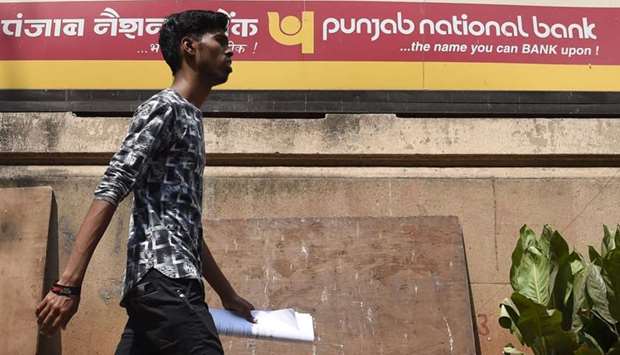An Indian man walks past a sign for the state-owned Punjab National Bank (PNB) in Mumbai
