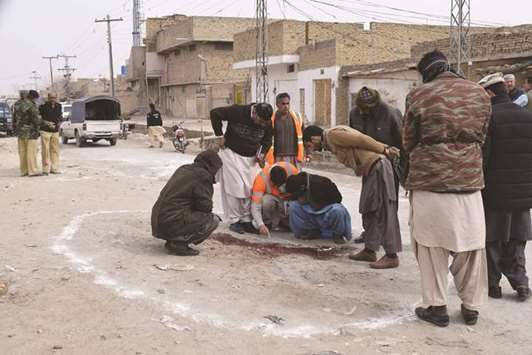 Plain-cloth security officials examine the site after an attack by gunmen on policemen in Quetta yesterday.
