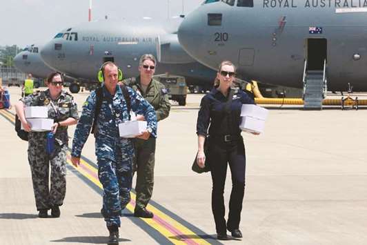Australian Defence Force and Department of Foreign Affairs and Trade personnel walking to a C-17A Globemaster aircraft at RAAF Amberley Airbase at Amberley with Australian aid destined for Tonga.