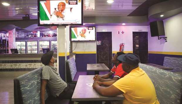 People watch South African President Jacob Zuma speaking on television during an interview with the South African Broadcasting Corporation (SABC) at the Union Buildings in Pretoria, yesterday.