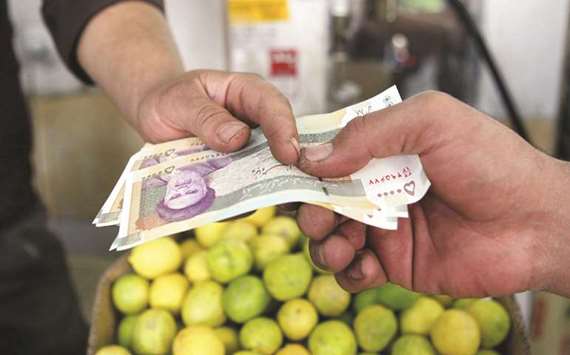 An Iranian man pays his rial 50,000 banknotes to a seller in a shop in Tehran (file). The currency reportedly fell to a record low of 50,000 to the dollar during  unregulated trading on Tuesday, according to state-run media. It strengthened to 47,170 yesterday but is still about 23% weaker than a year ago.