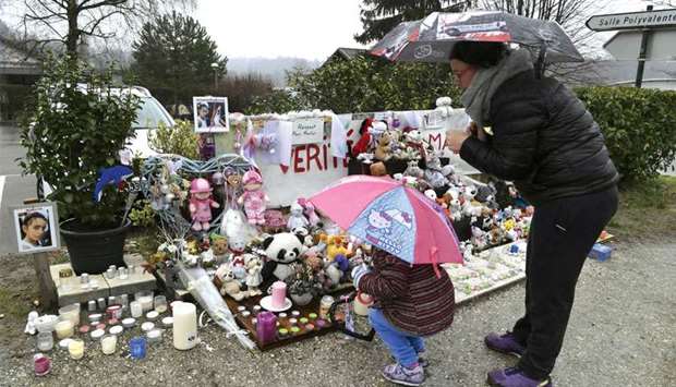 A woman and her daughter stand in front of candles, toys and messages displayed in tribute to eight-year-old Maelys de Araujo in Le Pont-de-Beauvoisin, the place where the schoolgirl was seen for the last time.