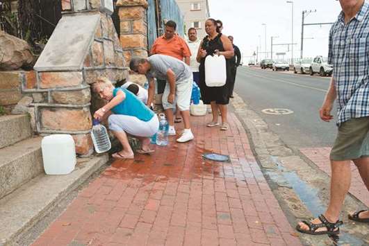 People collect drinking water from pipes fed by an underground spring, in St James, about 25km from the city centre, on January 19, 2018, in Cape Town.
