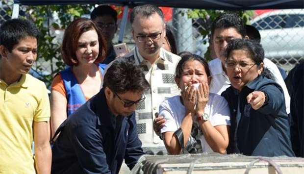 Jessica, sister of Filipina overseas worker Joanna Demafelis, cries in front of a wooden casket containing her sister's body after its arrival in Manila on Friday. Philippine Foreign Secretary Alan Peter Cayetano (centre) looks on.