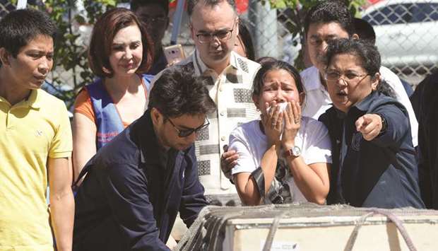 Jessica (second right), sister of Filipina overseas worker Joanna Demafelis, cries in front of a wooden casket containing her sisteru2019s body, shortly after its arrival at the international airport in Manila, yesterday.