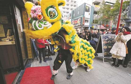 A Chinese lion dance troupe performs in front of a shop at Chinatown to celebrate the Lunar New Year in Yokohama, Japan.