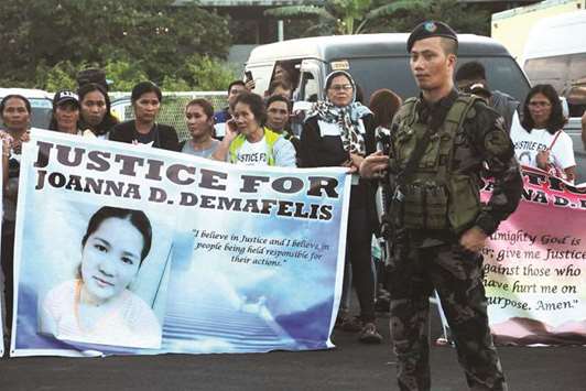 Relatives of Filipina worker Joanna Demafelis, hold banners as they wait for the arrival of Joannau2019s body from Manila at Iloilo International Airport.