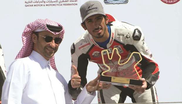 Qataru2019s Mishal al-Naimi receives the winneru2019s trophy after winning the first race of the third round of Qatar Superstock 600 as Qataru2019s Saeed al-Sulaiti, who won the second race of the day, looks on.