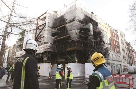 Firefighters look at the damage caused by a fire at a construction site in central London yesterday.