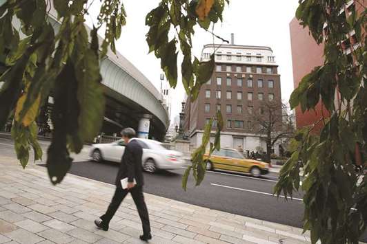 A pedestrian walks near the Nomura Holdings headquarters in Tokyo. Nomura and Aberdeen Standard Investments have a word of caution for investors marvelling at the  relative resilience of emerging debt markets in global selloff: the worst is still to come.
