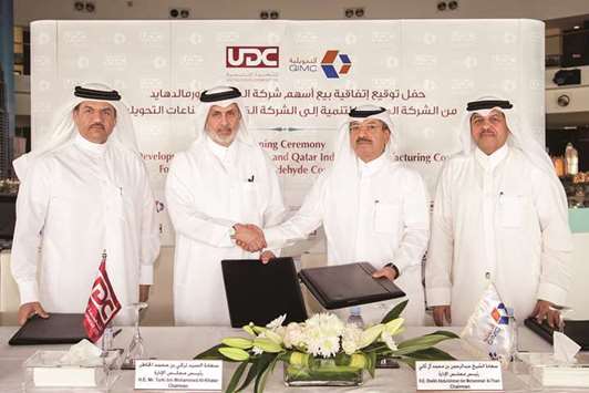 Sheikh AbdulRahman (second right) shakes hands with al-Khater as  al-Othman and al-Ansari look on during the sale deal signing under which QIMC acquired UDCu2019s stake in GFC.