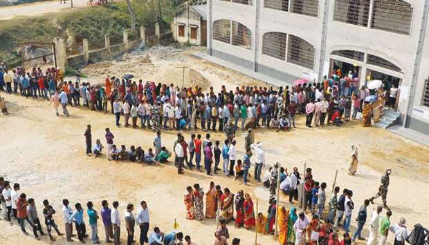 People stand in queues as they wait to cast their vote outside a polling station during Tripura state assembly election on the outskirts of Agartala, yesterday.
