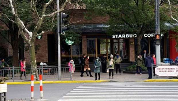 People walk in front of a Starbucks store after a vehicle caught fire and mounted the pavement, ploughing into pedestrians in a busy part of central Shanghai on Friday.