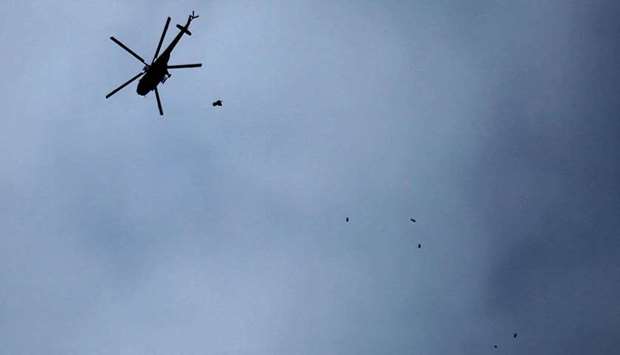 A picture taken on February 20, 2018 shows a Russian-made Syrian army attack helicopter dropping a payload over the rebel-held town of Arbin, in the besieged Eastern Ghouta region on the outskirts of the capital Damascus.