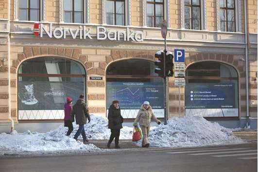 Pedestrians cross a road outside a Norvik Banka branch in Riga, Latvia. The bribery complaint against central bank chief Ilmars Rimsevics was made by a small Latvian lender, Norvik Bank, Prime Minister Maris Kucinskis said.