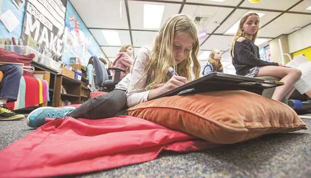 Amanda Garrett, 9, works on a project while lying on a mat during a fourth-grade class at Anderson Elementary School in Newport Beach, California.