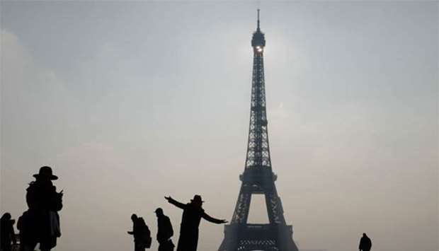 A woman poses next to the Eiffel Tower in Paris.