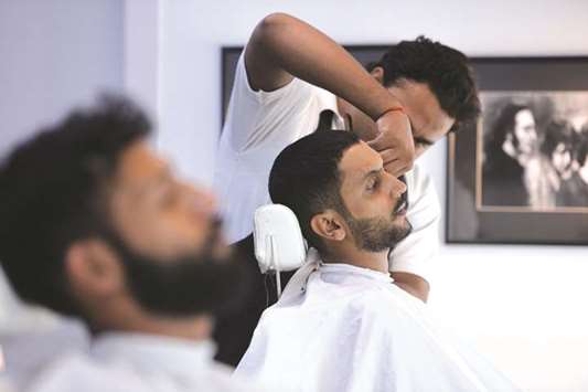 A hairdresser cuts the hair of a customer at a menu2019s salon in Islamabad.