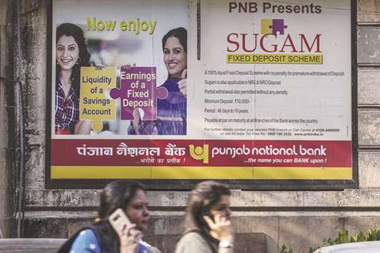 Pedestrians walk past an advertisement for Punjab National Bank (PNB) in Mumbai on February 14. As the fallout from Indiau2019s biggest bank fraud spreads and various government agencies move to investigate, one thing stands clear: The financial damage was exacerbated by a combination of inferior technology, weak risk management and insufficient regulatory oversight. Had the fraud been discovered a year earlier, the total amount would have been about $800mn lower.