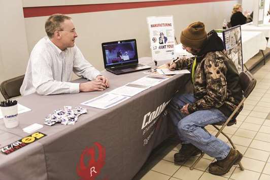 A job seeker (right) fills out an application at a resource fair in Belmont, New Hampshire (file). Initial claims for state unemployment benefits dropped 7,000 to a seasonally adjusted 222,000 for the week ended February 17, the Labour Department said yesterday.