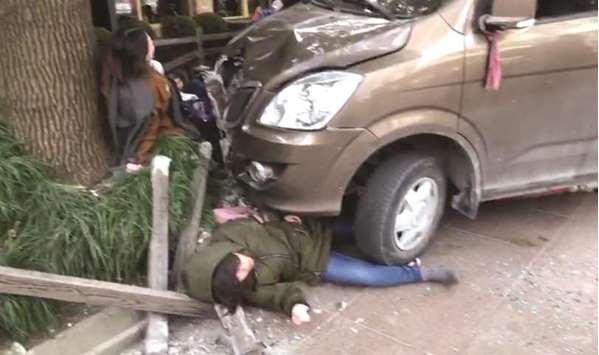This frame grab taken from video received by AFPTV from a witness yesterday shows injured people trapped between a van and a fence after the van caught fire and ploughed into pedestrians on a crowded pavement outside a Starbucks in Shanghai.