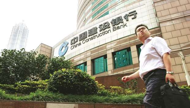 A man walks past China Construction Bank in Shanghai (file). Goldman Sachs Group and Morgan Stanley are among at least 16 brokerages that have raised their target prices for Chinau2019s second-largest bank this year.