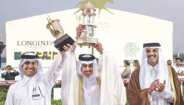 His Highness the Emir Sheikh Tamim bin Hamad al-Thani applauds as The Blue Eyeu2019s owner Khalifa bin Sheail al-Kuwari (centre) and trainer Jassim Mohamed Ghazali (left) lift their trophies after the six-year-old won HH The Emiru2019s Trophy (Gr1) yesterday.