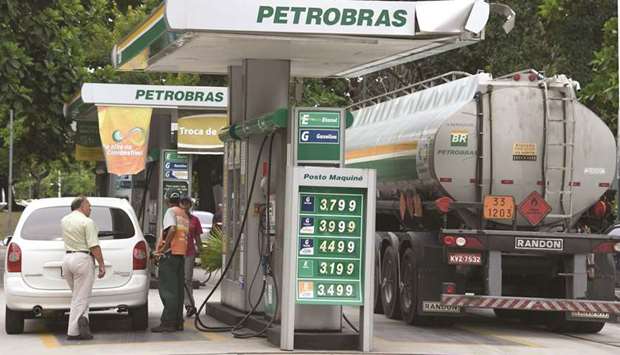 A man fuels up his car at a Petrobras station in downtown Rio de Janeiro (file). Fitch downgraded Brazil to BB-, three notches below investment grade and the same as Bolivia and Vietnam. The outlook is stable, Fitch said.