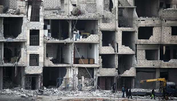 Syrians walk past destroyed buildings in Arbin in the rebel-held enclave of Eastern Ghouta