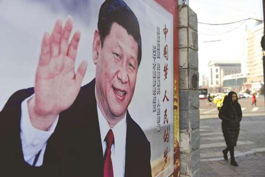 A woman walks past a poster of Chinese President Xi Jinping beside a street in Beijing yesterday.